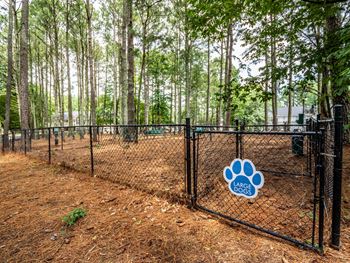 a dog park with a black fence and a blue and white dog paw sign on the fence